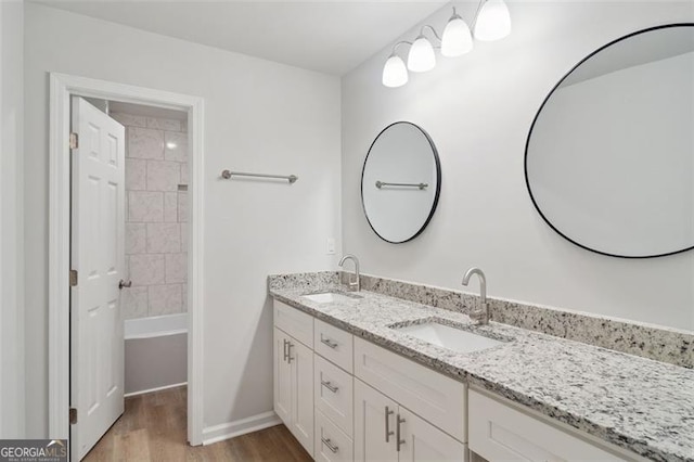 full bathroom featuring wood finished floors, double vanity, and baseboards