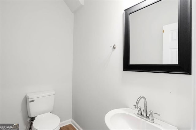 bathroom with a sink, toilet, and baseboards