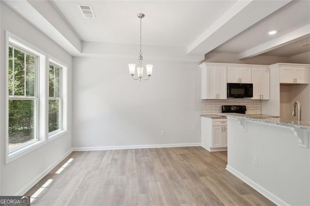 kitchen featuring black appliances, a kitchen breakfast bar, backsplash, a chandelier, and light wood-style floors