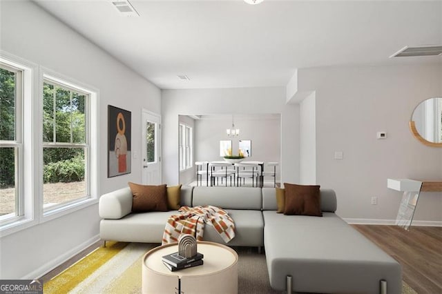 living room with baseboards, a chandelier, and wood finished floors
