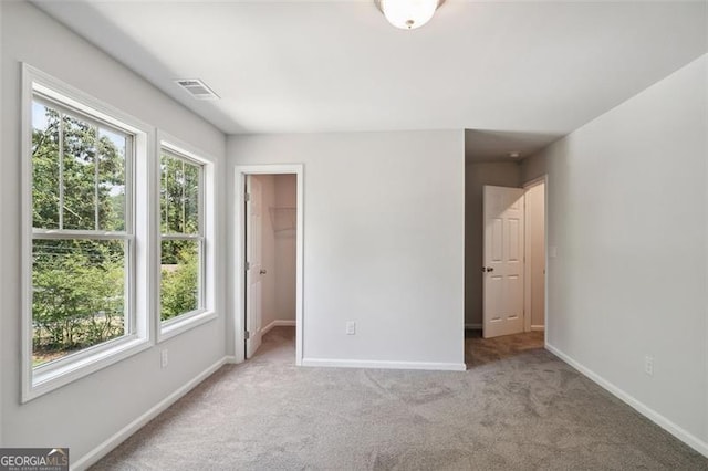 unfurnished bedroom with carpet, baseboards, and a walk in closet