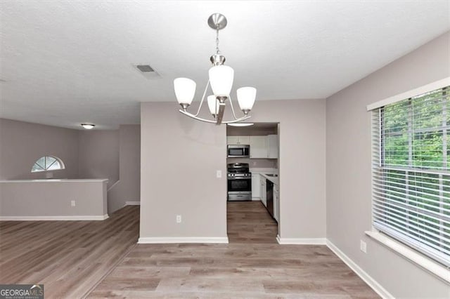 5290 Forest Downs Ln, Atlanta, GA 30349 - unfurnished dining area with a chandelier, light wood-type flooring, baseboards, and a textured ceiling