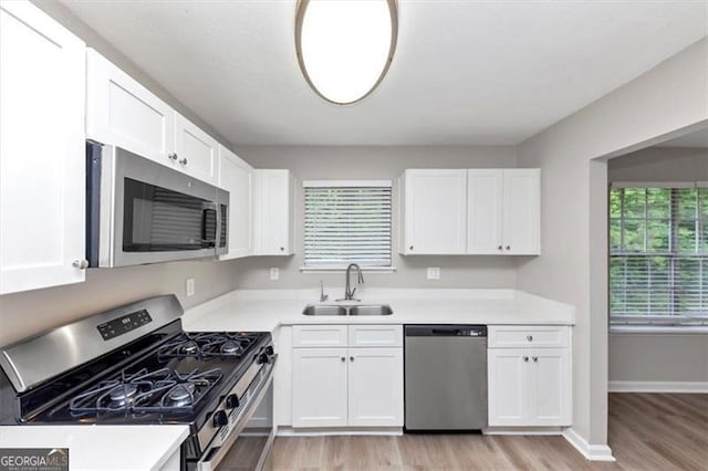 5290 Forest Downs Ln, Atlanta, GA 30349 - kitchen with appliances with stainless steel finishes, a sink, white cabinetry, light countertops, and light wood finished floors