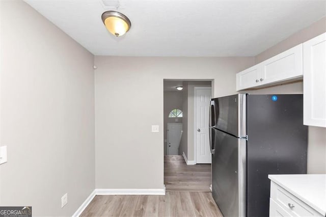 5290 Forest Downs Ln, Atlanta, GA 30349 - kitchen featuring freestanding refrigerator, white cabinetry, light wood-style floors, light countertops, and baseboards