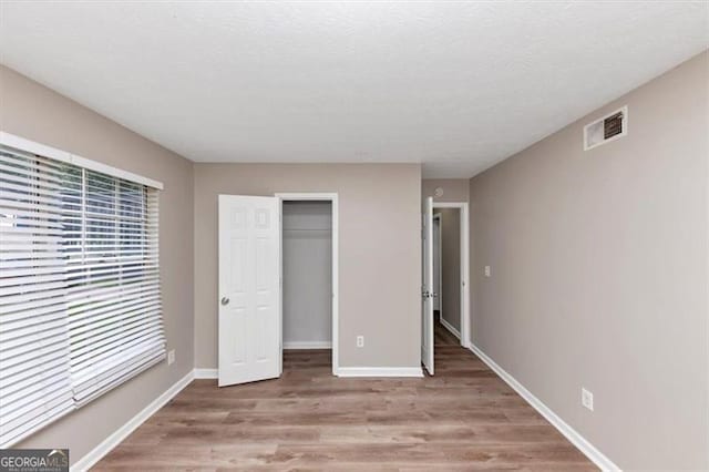 5290 Forest Downs Ln, Atlanta, GA 30349 - unfurnished bedroom with wood finished floors, baseboards, a closet, and a spacious closet