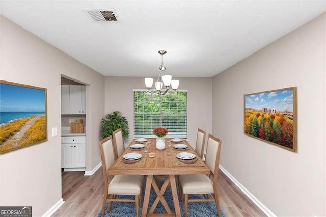 5290 Forest Downs Ln, Atlanta, GA 30349 - dining room featuring light wood-type flooring, a chandelier, baseboards, and a water view