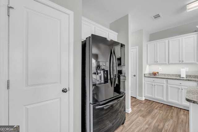 70 Wisteria Way, Winder, GA 30680 - kitchen with black fridge, white cabinets, light wood-type flooring, light stone countertops, and baseboards
