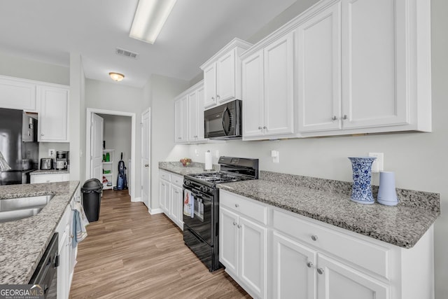70 Wisteria Way, Winder, GA 30680 - kitchen with black appliances, white cabinetry, light wood-type flooring, light stone countertops, and a sink