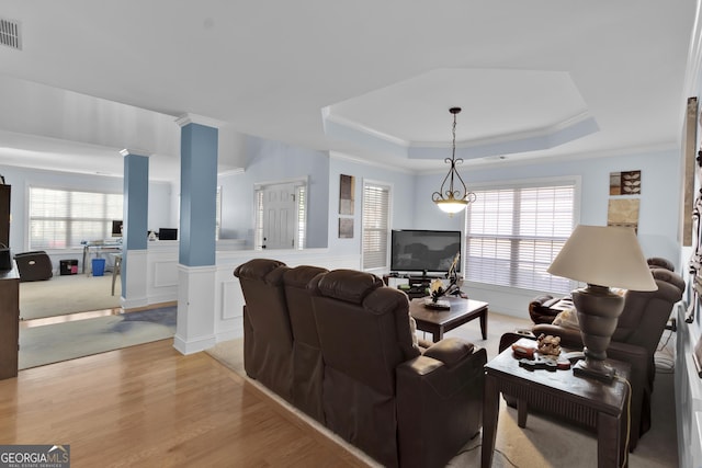 1885 Hickory Station Cir, Snellville, GA 30078 - living room featuring decorative columns, a raised ceiling, light wood-type flooring, wainscoting, and healthy amount of natural light