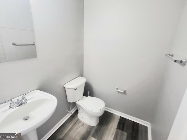 bathroom with a sink, toilet, wood finished floors, and baseboards