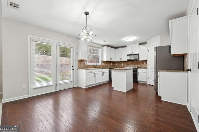 1736 Dylan Pl, Lawrenceville, GA 30043 - kitchen with appliances with stainless steel finishes, tasteful backsplash, a center island, dark wood-type flooring, and white cabinetry