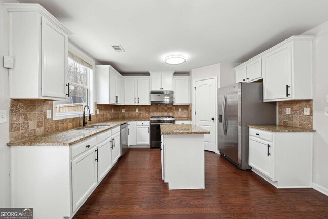 1736 Dylan Pl, Lawrenceville, GA 30043 - kitchen featuring stainless steel appliances, backsplash, dark wood-style floors, light stone counters, and white cabinets
