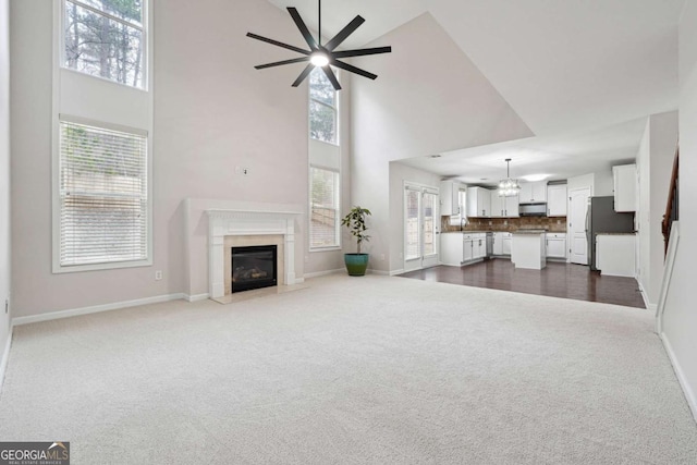 1736 Dylan Pl, Lawrenceville, GA 30043 - living area with dark carpet, a towering ceiling, a fireplace, ceiling fan, and a chandelier