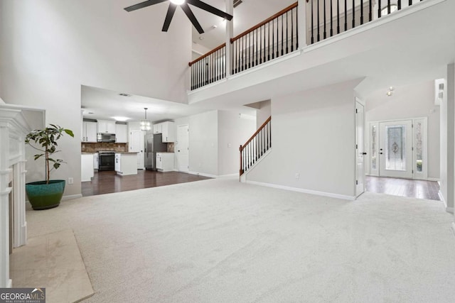 1736 Dylan Pl, Lawrenceville, GA 30043 - unfurnished living room featuring dark carpet, a high ceiling, a ceiling fan, stairs, and a fireplace