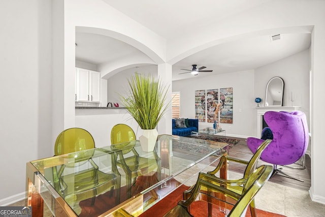 dining area featuring a ceiling fan, baseboards, and arched walkways