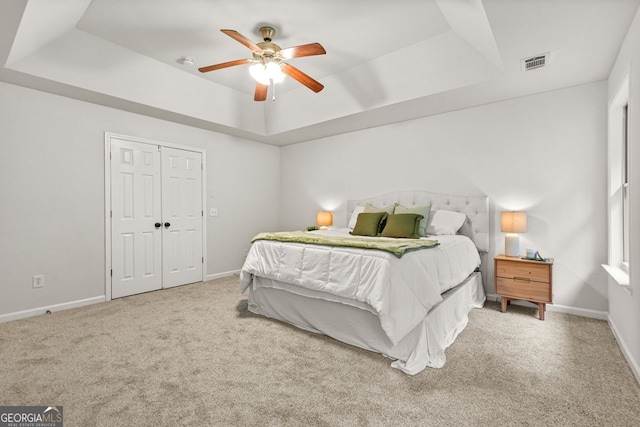 bedroom with a raised ceiling, carpet floors, and baseboards