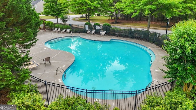 community pool featuring a patio area and view of scattered trees