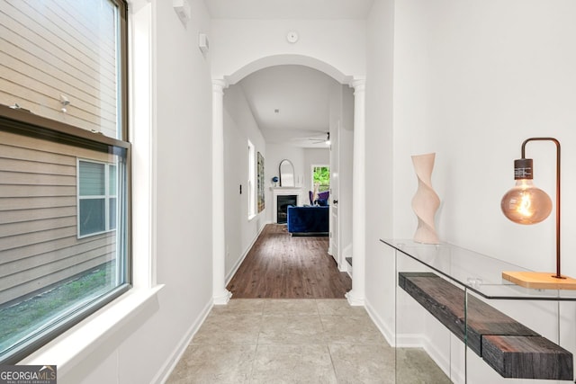 corridor with ornate columns, arched walkways, light tile patterned floors, and baseboards