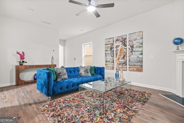 living room with wood finished floors, a ceiling fan, and baseboards