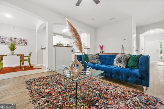 living area featuring arched walkways, light wood-style flooring, ceiling fan, baseboards, and recessed lighting