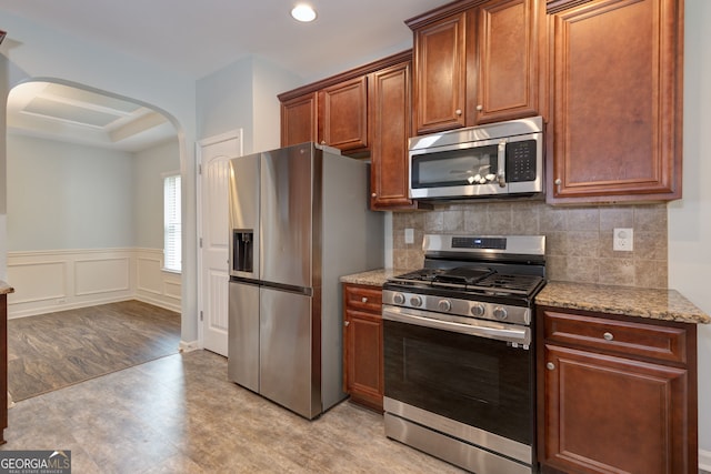 49 Torero Trl, Newnan, GA 30263 - kitchen featuring stainless steel appliances, arched walkways, light wood finished floors, light stone countertops, and tasteful backsplash