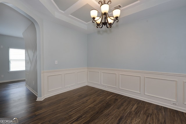 49 Torero Trl, Newnan, GA 30263 - empty room with a chandelier, dark wood finished floors, coffered ceiling, arched walkways, and a wainscoted wall