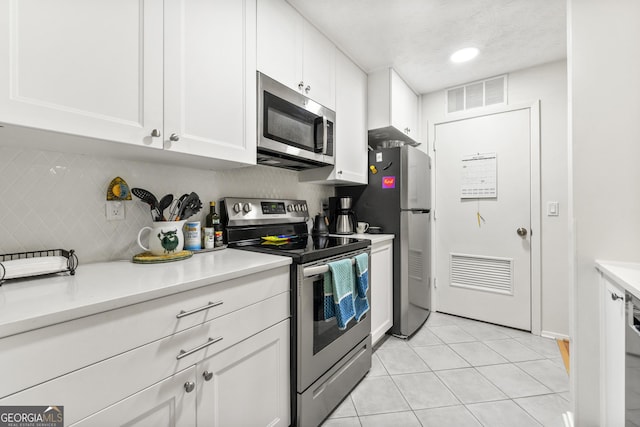 1424 Tuxworth Cir, Decatur, GA 30033 - kitchen featuring appliances with stainless steel finishes, light countertops, white cabinetry, light tile patterned floors, and decorative backsplash