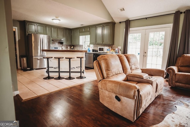 living room featuring light wood-style flooring, lofted ceiling, and french doors