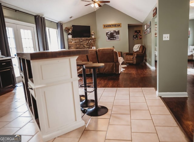 kitchen featuring a ceiling fan, vaulted ceiling, open floor plan, and dark cabinetry