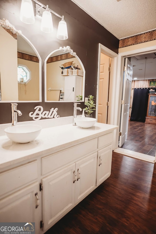 full bathroom featuring wood finished floors, double vanity, and a textured ceiling