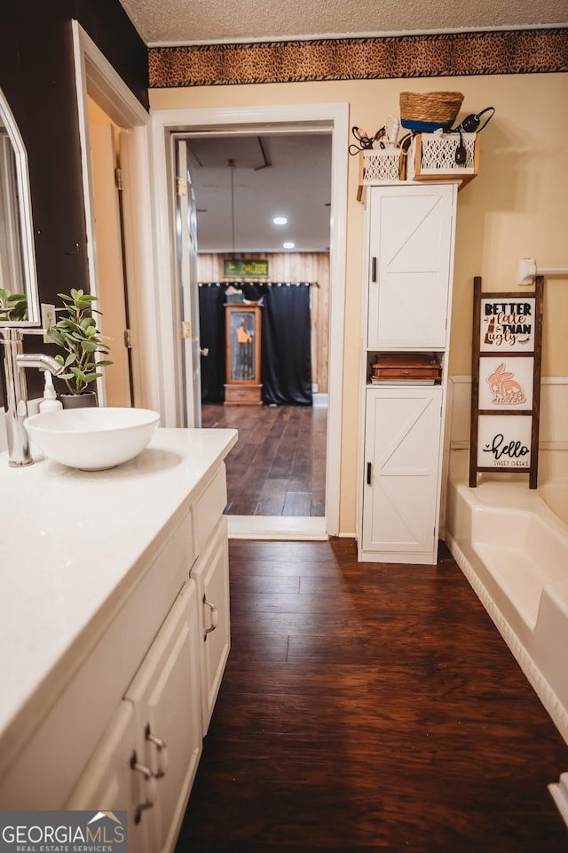 full bath with wood finished floors, vanity, and a tub to relax in