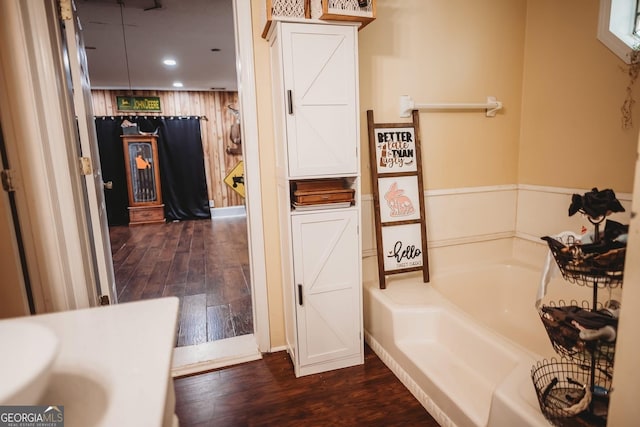 bathroom featuring hardwood / wood-style floors, a bath, recessed lighting, and a wainscoted wall