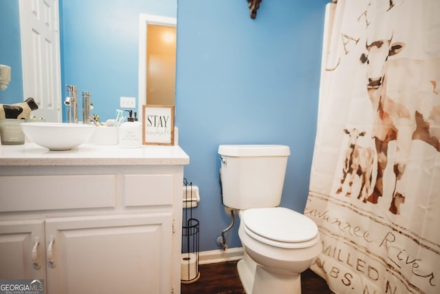bathroom with vanity, toilet, baseboards, a shower with shower curtain, and wood finished floors