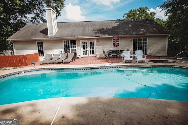 view of swimming pool featuring french doors, fence, an in-ground hot tub, and outdoor dining space