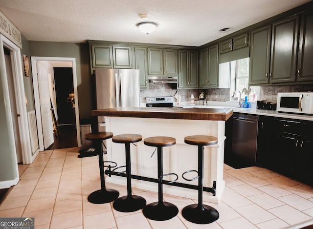 kitchen featuring stainless steel appliances, under cabinet range hood, decorative backsplash, and a center island