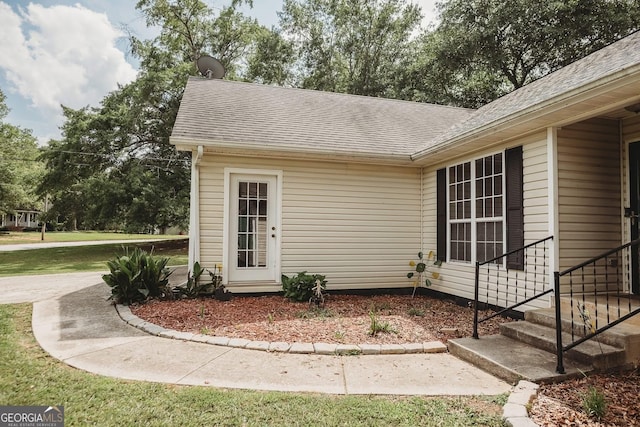 doorway to property with a shingled roof