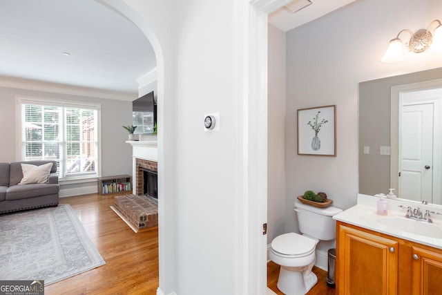 855 Mountain View Ter NW, Marietta, GA 30064 - bathroom featuring vanity, wood finished floors, toilet, crown molding, and a brick fireplace