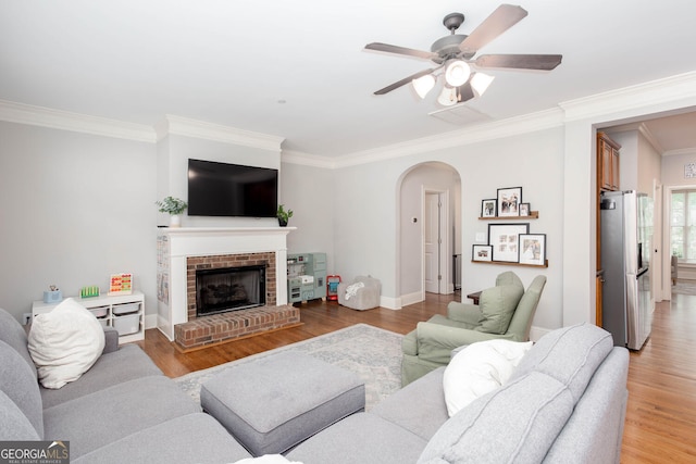 855 Mountain View Ter NW, Marietta, GA 30064 - living room featuring arched walkways, ornamental molding, light wood-style floors, a ceiling fan, and a fireplace