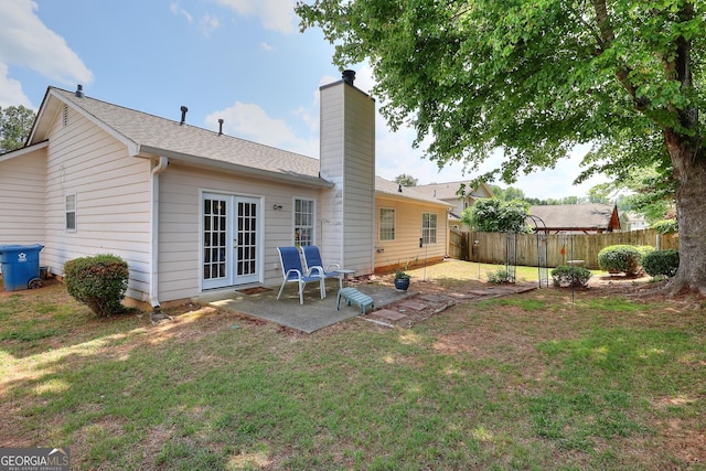 rear view of property featuring a patio, a chimney, french doors, and a shingled roof