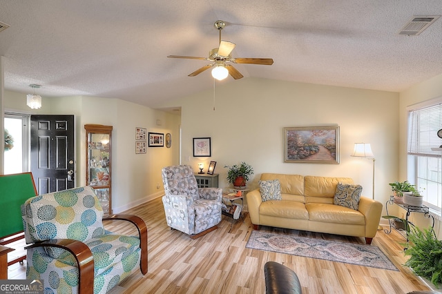living area with a ceiling fan, wood finished floors, lofted ceiling, baseboards, and a textured ceiling