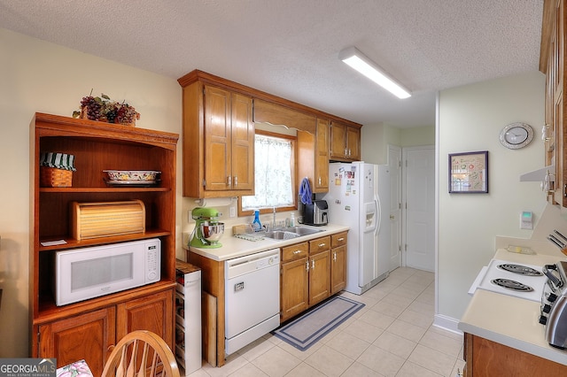 kitchen with white appliances, a sink, a textured ceiling, brown cabinets, and light tile patterned floors