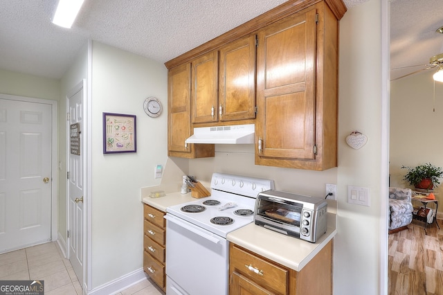 kitchen featuring under cabinet range hood, white electric stove, brown cabinetry, light countertops, and a ceiling fan