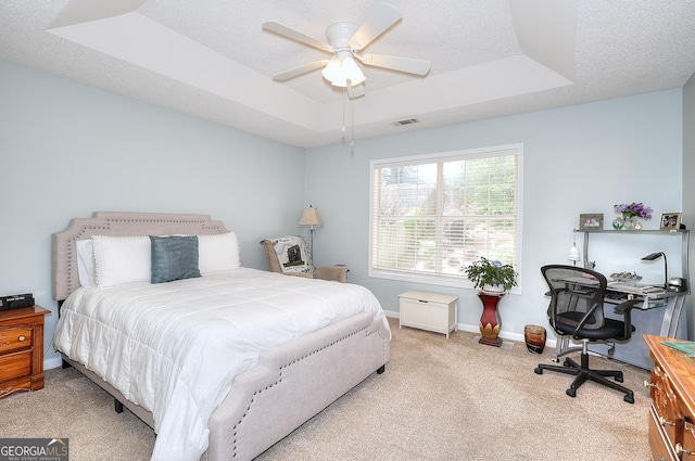 carpeted bedroom with a raised ceiling, an office area, baseboards, a ceiling fan, and a textured ceiling