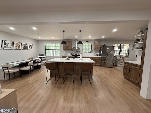 kitchen featuring stainless steel fridge with ice dispenser, wall chimney range hood, recessed lighting, light countertops, and light wood-style flooring