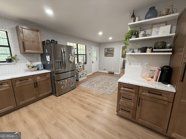 kitchen featuring stainless steel fridge with ice dispenser, light wood-type flooring, open shelves, recessed lighting, and backsplash