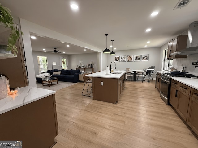 kitchen featuring wall chimney exhaust hood, gas stove, recessed lighting, backsplash, and light wood-style floors