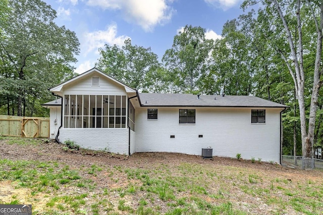 back of property featuring a sunroom, brick siding, and central AC unit