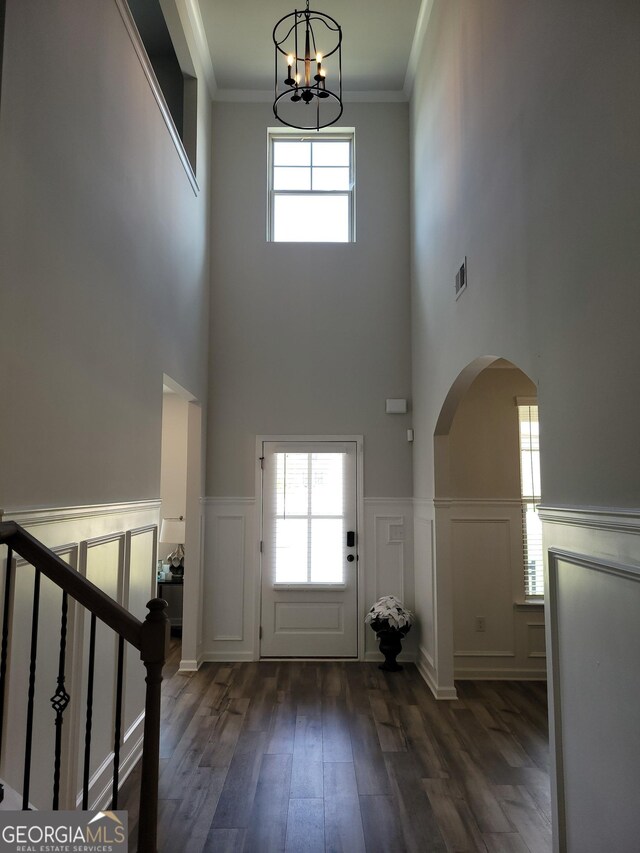 436 Lothbury Ave, Locust Grove, GA 30248 - foyer featuring a chandelier, arched walkways, a high ceiling, dark wood-type flooring, and a wainscoted wall