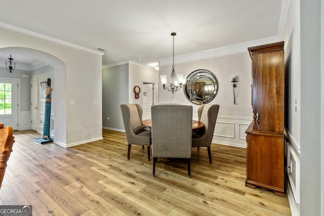 733 Firefly Ct, Griffin, GA 30223 - dining space with arched walkways, a chandelier, light wood-style flooring, a decorative wall, and crown molding