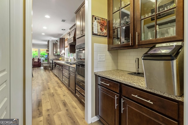 733 Firefly Ct, Griffin, GA 30223 - kitchen featuring light wood finished floors, dark brown cabinetry, light stone countertops, tasteful backsplash, and recessed lighting